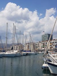 Sailboats moored at harbor against sky