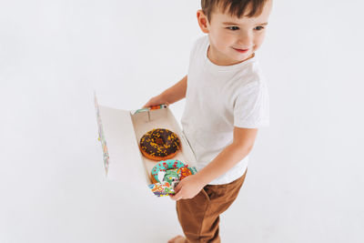 Funny cute toddler boy with box of donuts on white background, studio shot