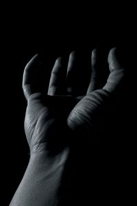 Close-up of human hand against black background