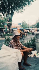 Full length portrait of woman sitting on sidewalk in city