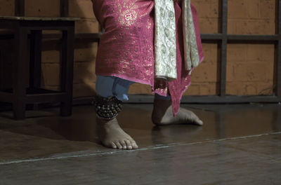 Low section of woman standing on floor with ghungroo