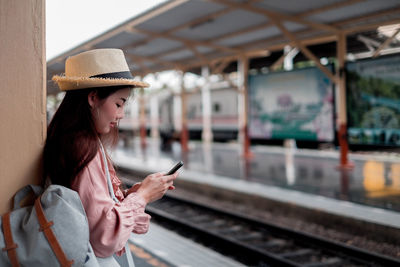 Young woman using mobile phone at railroad station