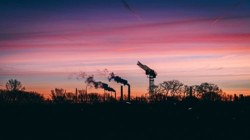 Silhouette trees on field against sky during sunset