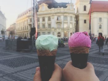 Cropped image of hands holding ice cream in city
