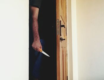 Midsection of man holding knife while standing at doorway