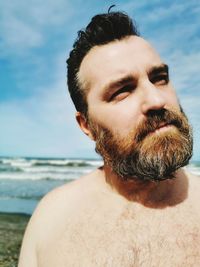 Portrait of shirtless man in sea against sky