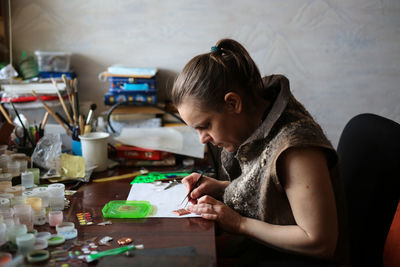 Master at table spreads a drawing on a copper plate, work and a home workshop, the process of making