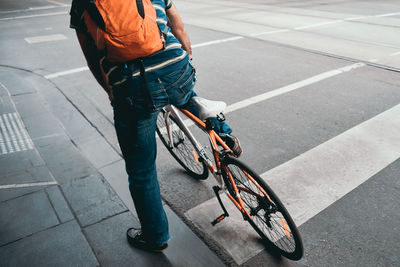Low section of man with bicycle on road