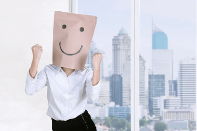 Businesswoman wearing paper bag with anthropomorphic face in office