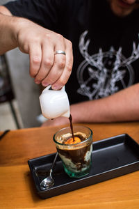 Close-up of hand pouring coffee in cup