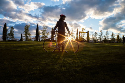 Man riding bicycle on field against sky