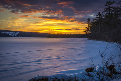 Scenic view of frozen lake against sky during sunset