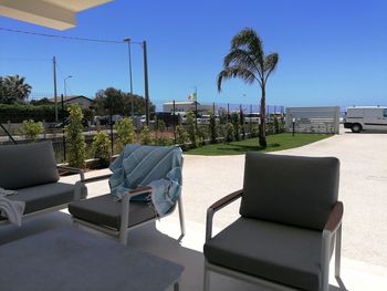 Chairs by swimming pool against sky