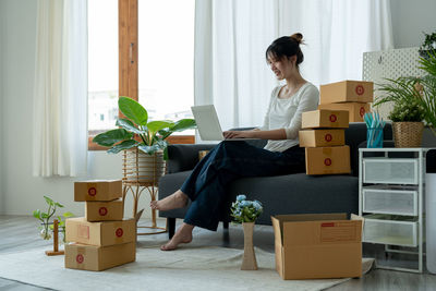 Side view of woman using laptop while sitting on sofa at home