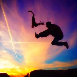 Low angle view of woman jumping against cloudy sky