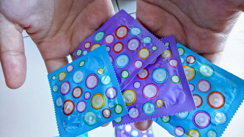 Cropped hands holding condoms indoors
