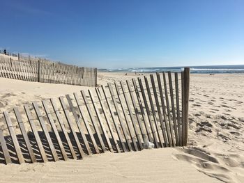 Wooden posts on beach against clear sky