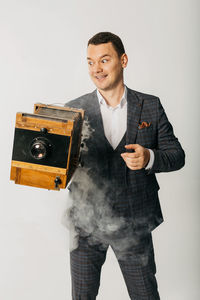 Young man holding camera over white background