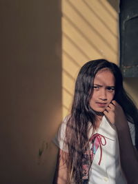 Portrait of young woman standing against wall