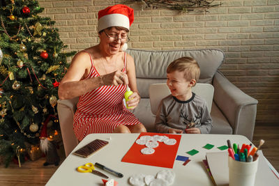 Smiling boy with grandmother decorating greeting card at home