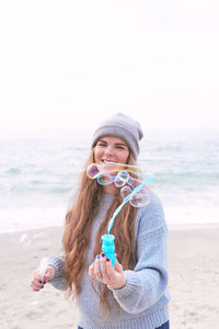 Happy young woman with long hair having fun with bubbles in autumn at the beach person