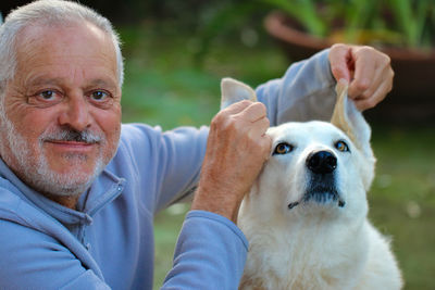 Portrait of man holding dog ears