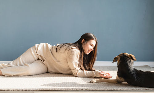 Beautiful brunette woman with playful mixed breed dog, embracing and having fun at home