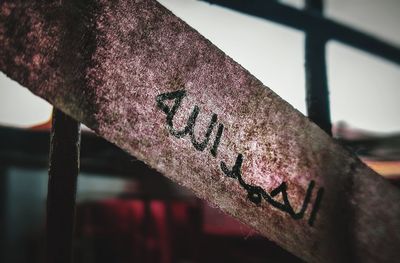 Close-up of rusty sign on railing