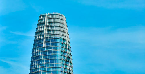 Low angle view of skyscraper against blue sky