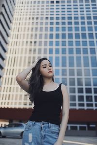 Young woman standing against buildings in city