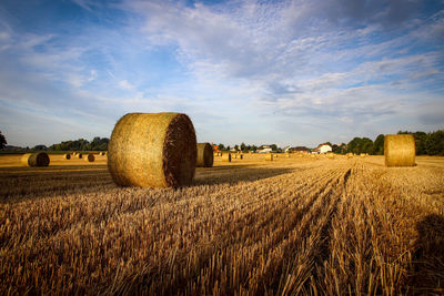 Hay bales on field against sky