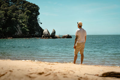 Rear view of man standing at beach against sky
