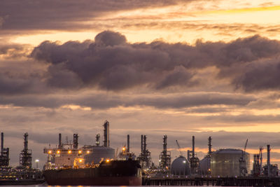 Illuminated factory against sky during sunset