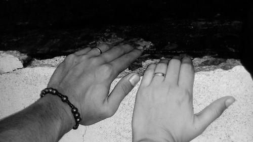 Close-up of couple hands on sand at beach