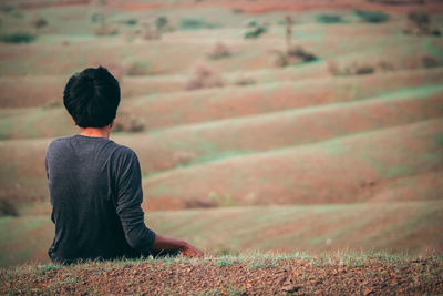 Rear view of man sitting on field