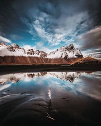 Scenic view of lake by snowcapped mountains against sky