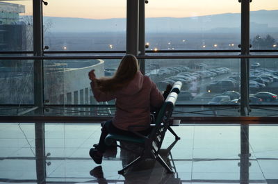 Rear view of woman sitting on window at airport