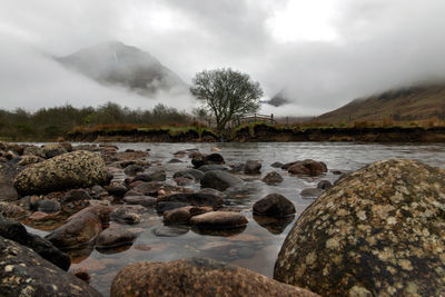 Rocks by river against sky