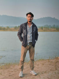 Portrait of young man standing against lake