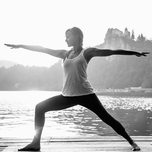 Young woman doing yoga on pier over lake