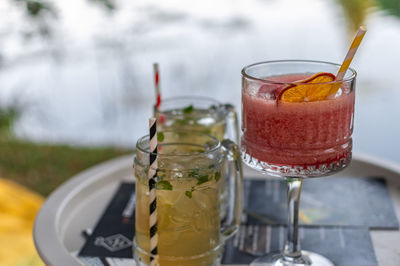 Close-up of cocktails in vintage glasses and jars on white pallet table in bar