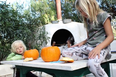 Siblings with pumpkins at table during halloween