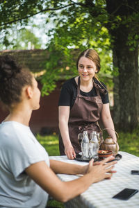 Smiling waitress looking at customer sitting in restaurant