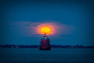 Lighthouse by sea against sky at night