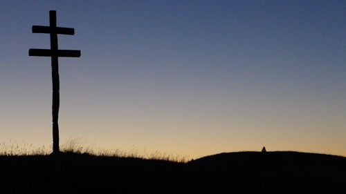 Silhouette cross against sky during sunset