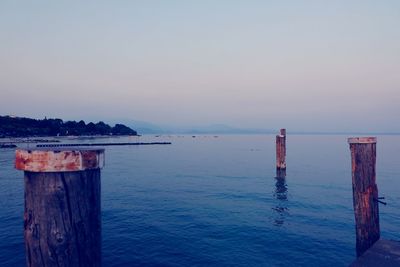 Wooden posts in sea against sky