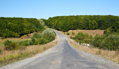 Wide shot of empty country road along countryside landscape