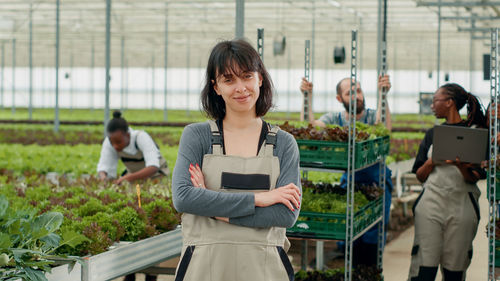Rear view of young woman standing in greenhouse