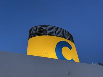 Low angle view of yellow sign against clear sky