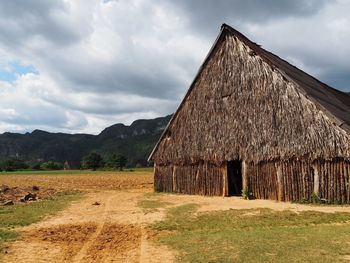 Wooden house on field against sky